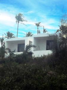 una casa blanca con palmeras delante en Duna Serena Tiny Houses, en Praia do Tofo