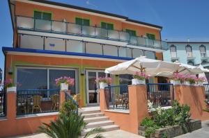un edificio con un patio con mesas y sombrillas en Hotel Giacomazzo en Caorle
