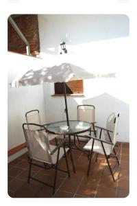 Refugio tranquilo cerca de las piscinas في كانديليدا: طاولة زجاجية مع كراسي ومظلة