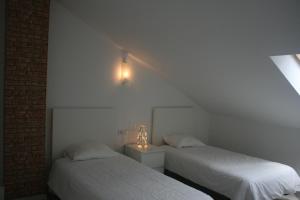 a bedroom with two beds and a light on the wall at Pensión El Ansar in Cartes