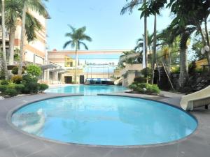 a large blue pool with palm trees and a building at Queen Margarette Hotel in Camp Wilhelm