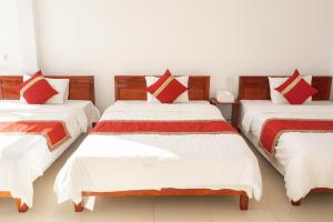 a room with three beds with white and red pillows at Thành Luân Hotel in Bak Kan