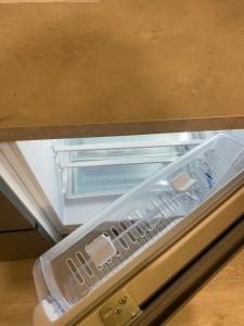 Ein leerer Kühlschrank mit offener Tür steht unter einem Tisch in der Unterkunft Apartment Modern & Cozy - City Center Saldus in Saldus