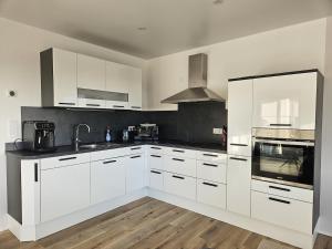 Una cocina con gabinetes blancos y electrodomésticos de acero inoxidable. en Moderne 3-Zimmer-Wohnung mit Panoramablick, en Bad Berleburg