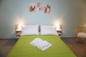 Farina rooms and apartments في San Nicola La Strada: سرير اخضر عليه منشفتين بيضاء