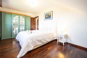 a bedroom with a large white bed and a wooden floor at Casa Costera Gijón By Silastur in Gijón