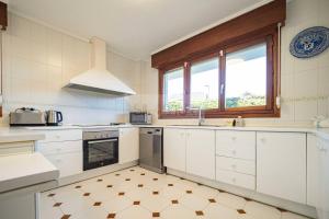 a kitchen with white cabinets and a window at Casa Costera Gijón By Silastur in Gijón