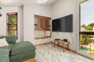 een woonkamer met een groene bank en een flatscreen-tv bij Beautiful air-conditioned house and heated pool in La Celle-sous-Gouzon