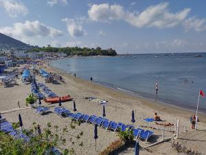 a beach with a bunch of chairs and people on it at Appartamento panoramico la rosa dei venti-Libeccio in Ischia