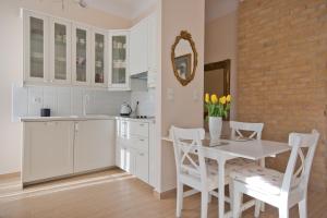 a kitchen with white cabinets and a white table and chairs at Imperial Apartments - Classic in Sopot