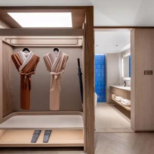 a bathroom with a closet with shirts and a sink at Orange Crystal Qingdao Taidong Pedestrian Street Yan'an Third Road Hotel in Qingdao