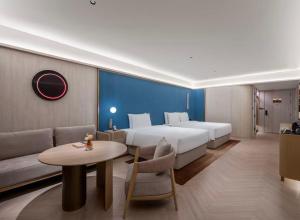 a hotel room with a bed and a table and a couch at Orange Crystal Qingdao Taidong Pedestrian Street Yan'an Third Road Hotel in Qingdao