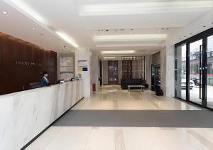 City Comfort Inn Xiangyang Railway Station في شيانغيانغ: امرأة تقف عند المنضدة في الردهة