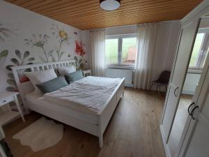 a bedroom with a white bed and a window at Ferienhaus Dorfidylle in Oberzent