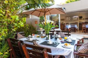 a table set for breakfast on a patio with an umbrella at Kingfisher GuestHouse in Port Elizabeth
