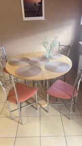 een houten tafel met vier stoelen en een vaas erop bij Makowa 2 Street in Konin