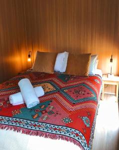 a bed with a red blanket and pillows on it at Dreamseed Cabin by Tiny Away in Yandina +7 photos