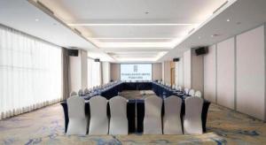 uma sala de conferências com uma mesa, cadeiras e uma tela em Rezen Hotel Huaxia Xiamen em Xiamen