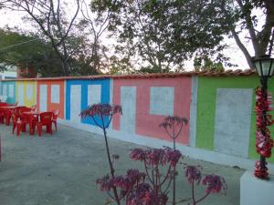 a row of colorful buildings with tables and purple flowers at Pousada Villa Bella in Palmeiras