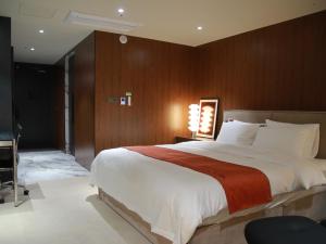 Un dormitorio con una cama grande con una pared de madera. en 구미 더혜밀호텔, en Gumi