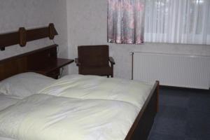 a bedroom with a bed and a chair and a window at Hotel-Gasthaus Burmester in Heidenau
