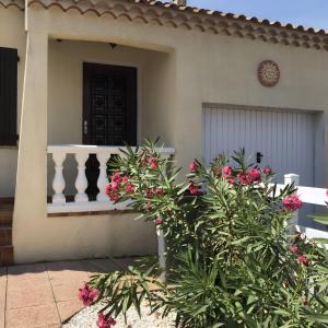 ein Haus mit einer Veranda mit rosa Blumen davor in der Unterkunft Gîtes Villa Beau Soleil Agde in Agde