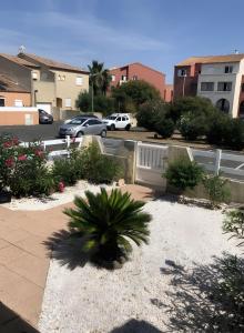 einen Garten mit einer Palme auf einem Parkplatz in der Unterkunft Gîtes Villa Beau Soleil Agde in Agde