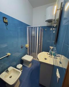 a blue tiled bathroom with a sink and a toilet at GC Petit Palais Lampedusa in Lampedusa