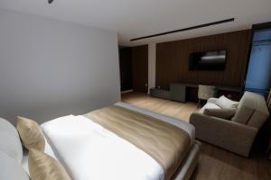 a bedroom with a bed and a couch and a tv at Velura Hotel in Ferizaj