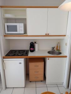 a small kitchen with a microwave and a sink at les pieds dans l'eau 1-Piscine chauffée in Le Barcarès