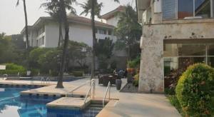 a house with a swimming pool next to a building at Jelita Bandara Hotel Airport in Ulin