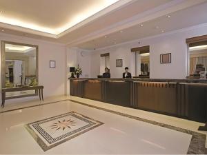 Un vestíbulo de hotel con un mostrador de recepción y dos hombres en Le Beringin, en Salatiga