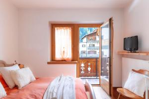 a bedroom with a bed and a tv and a window at The Dolomites Lodge in San Pietro di Cadore