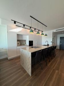 a kitchen with a large island with black bar chairs at Stylish Penthouse Beach Front in Ashkelon