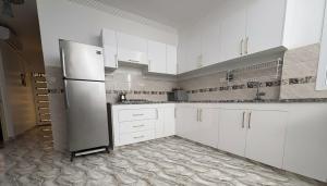 a kitchen with white cabinets and a refrigerator at Maison Luxueux et Spacieux in Oujda