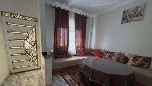 a bedroom with a bed and a window with red curtains at Maison Luxueux et Spacieux in Oujda