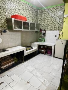 a kitchen with white tile floors and a refrigerator at The wilsian - Syariah guest house in Sengkaling