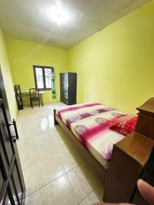 a bedroom with a bed in a room with yellow walls at The wilsian - Syariah guest house in Sengkaling