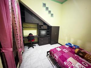 a bedroom with a bed and a desk with a computer at The wilsian - Syariah guest house in Sengkaling