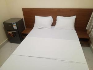 ein Bett mit zwei weißen Kissen und einem hölzernen Kopfteil in der Unterkunft Résidence Keur Mame Seye 4 in Dakar + 15 Fotos