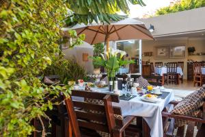 a dining table with an umbrella on a patio at Kingfisher GuestHouse in Port Elizabeth