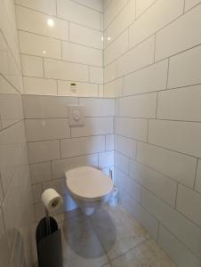 a bathroom with a toilet in a white tiled wall at Chambre familiale, Les Brimbelles in Rehaupal
