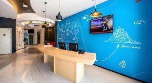 an office with a blue wall with a desk and a tv at ibis Wuxi Jiangnan University in Wuxi