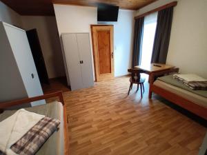 Habitación con 2 camas, escritorio y puerta. en Pension Waldfrieden, en Steinhaus am Semmering