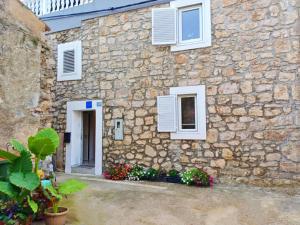 un bâtiment en pierre avec des fenêtres blanches et des fleurs devant dans l'établissement Casa del Sole - Ugljan Island, à Poljana