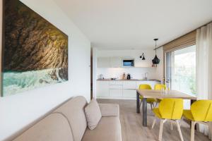 ein Wohnzimmer und eine Küche mit einem Tisch und gelben Stühlen in der Unterkunft Art & Nature Chalet Anna in Schenna