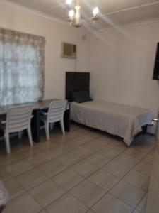 een slaapkamer met een bed, een tafel en stoelen bij Prior guest house in Pinetown