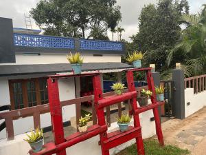 Eine rote Bank mit Topfpflanzen darauf neben einem Gebäude in der Unterkunft Tulips villa in Mānantoddy + 8 Fotos