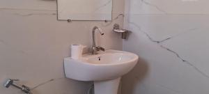 Hotel Anmol Palace في غازي آباد: حمام أبيض مع حوض ومرآة