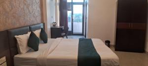 Hotel Anmol Palace في غازي آباد: غرفة نوم بسرير كبير مع ملاءات ووسائد بيضاء